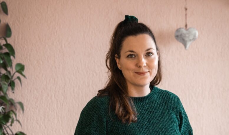 Linda Kaufmann Portraitfoto, lächelnd, Herz im Hintergrund